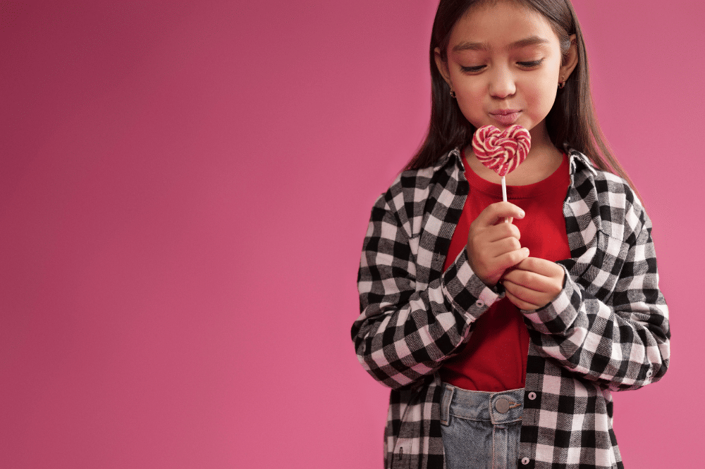 Anak perempuan sedang menatap permen berbentuk hati