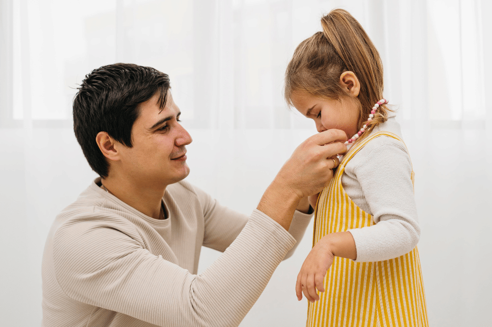 Papa sedang memakaikan kalung pada anak perempuannya menunjukkan kedekatan mereka