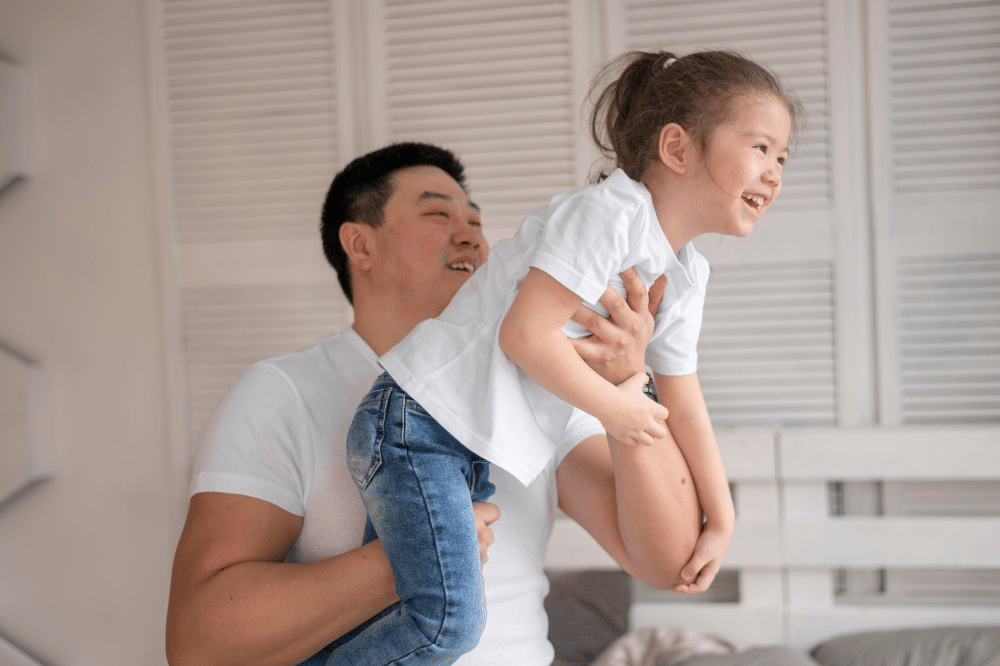 Papa bermain dengan anak perempuannya yang merasa aman dan nyaman