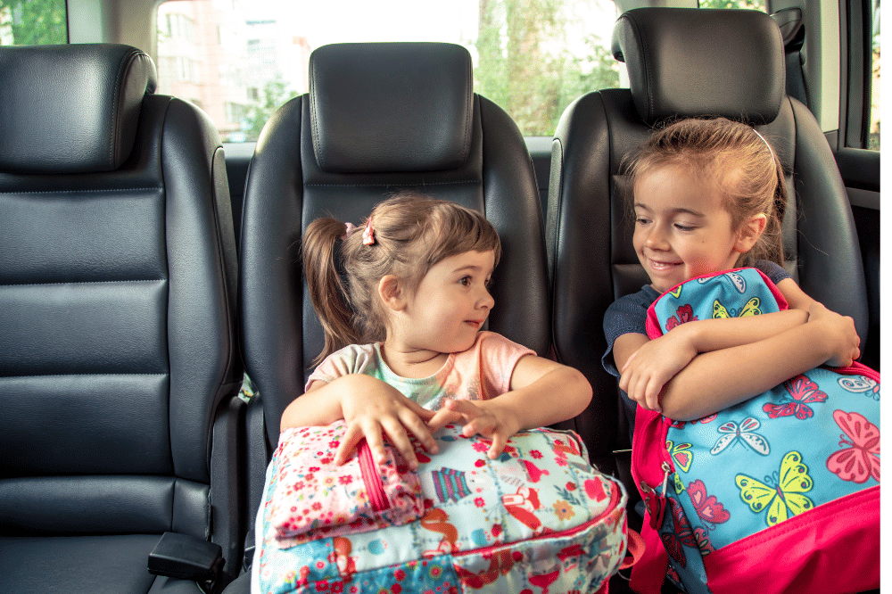 dua anak duduk di belakang mobil