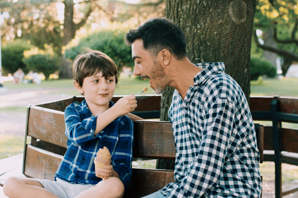 Anak dan Papa sedang berbincang sambil makan es krim di taman