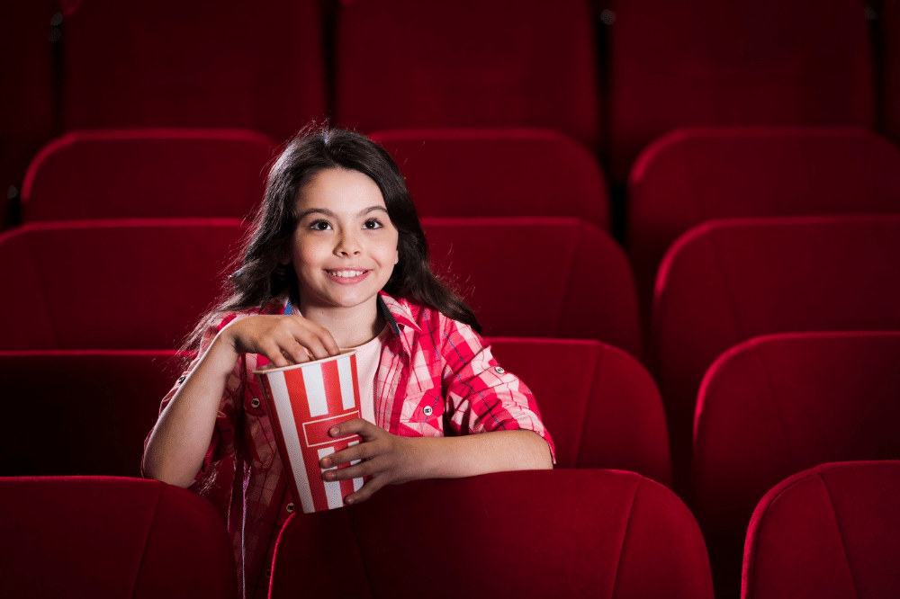 Anak perempuan sedang menonton film di bioskop
