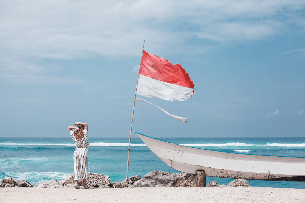 Seseorang sedang di pantai yang disebelah terdapat bendera merah putih
