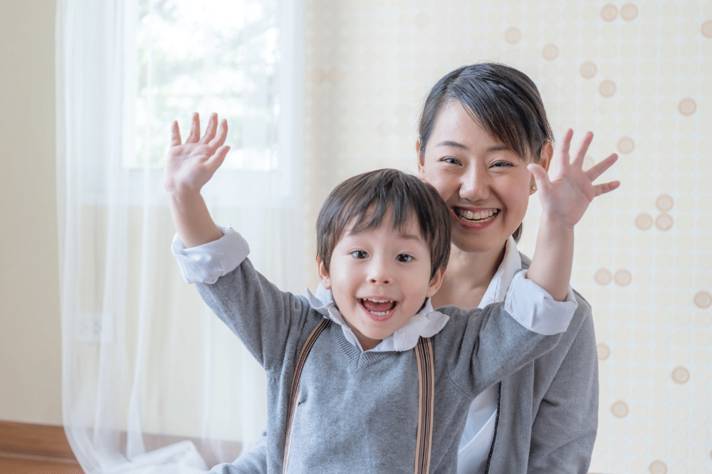 Anak laki-laki mengangkat kedua tangannya dengan semangat dipangkuan Mama