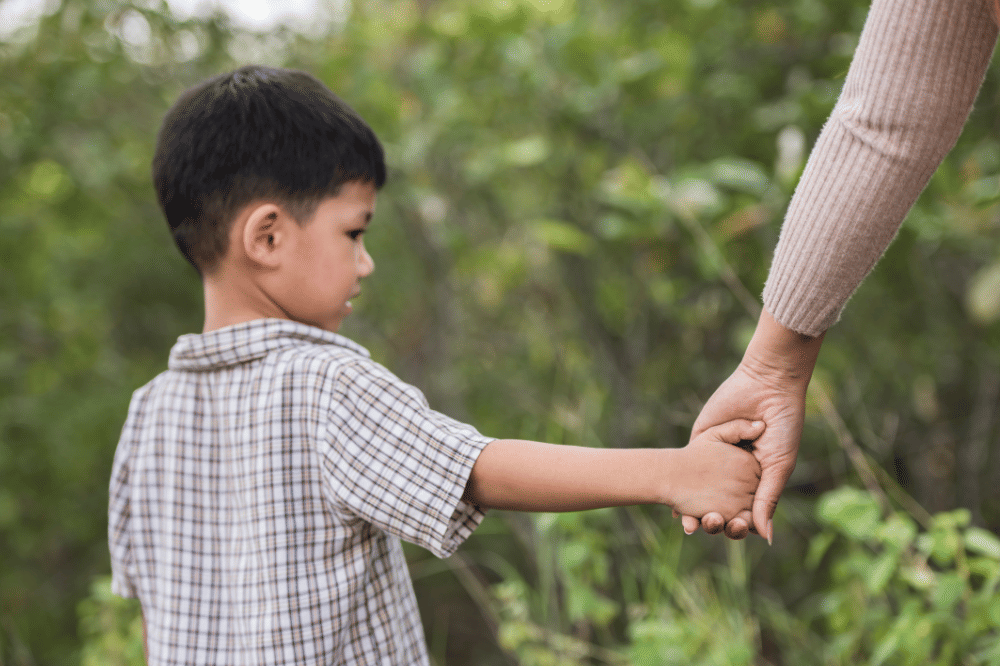 Anak laki- laki sedng menggandeng Mama