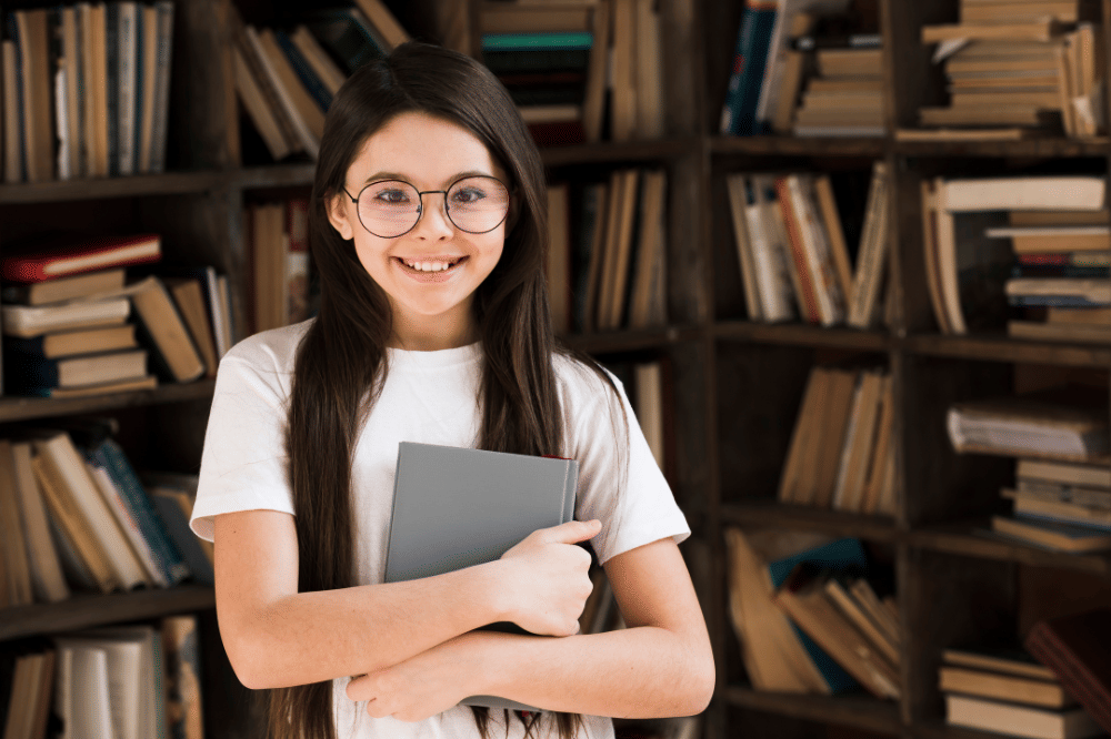 Seorang anak perempuan memegang buku di perpustakaan