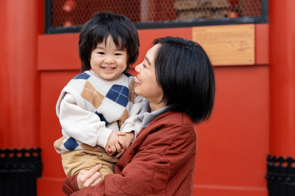 Mama sedang menatap anak laki-laki yang sedang digendong dan terlihat bahagia