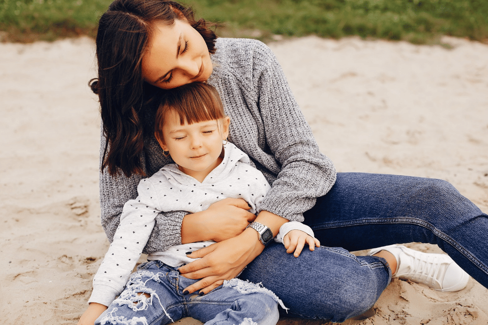 Anak perempuan duduk sambil dipeluk Mama