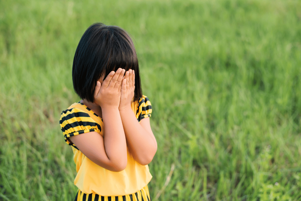 Anak perempuan sedang menutup mukanya dengan kedua tangannya