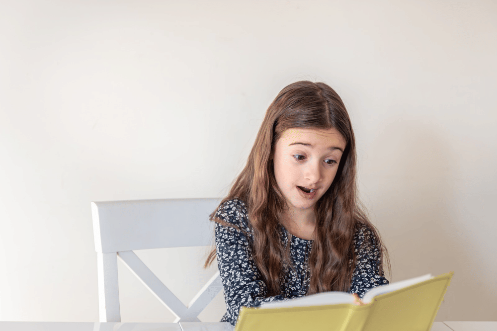 Anak perempuan sedang belajar sambil mempraktikkannya dengan berbicara