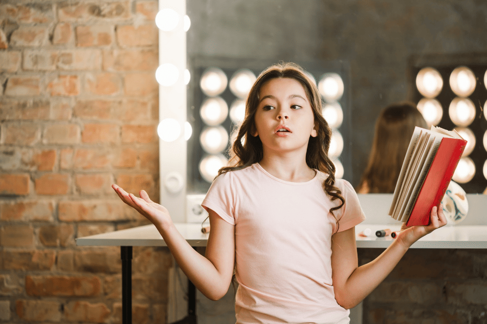 Anak perempuan sedang memegang buku dan latihan untuk mengucapkannya