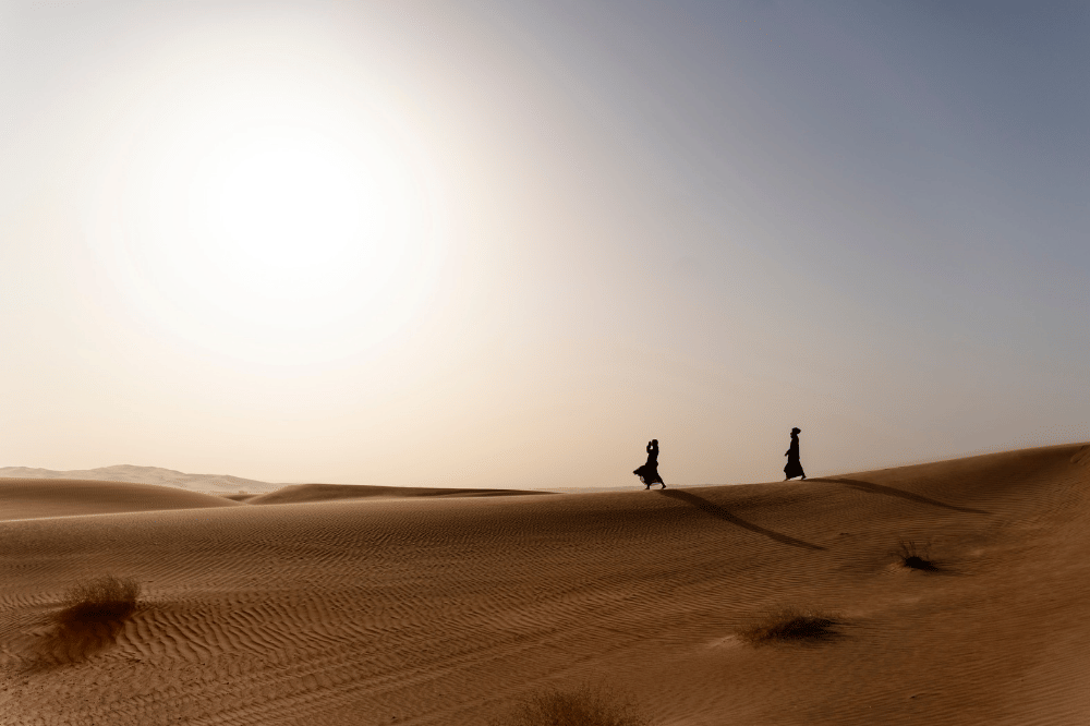 Dua orang terlihat berjalan di gurun pasir