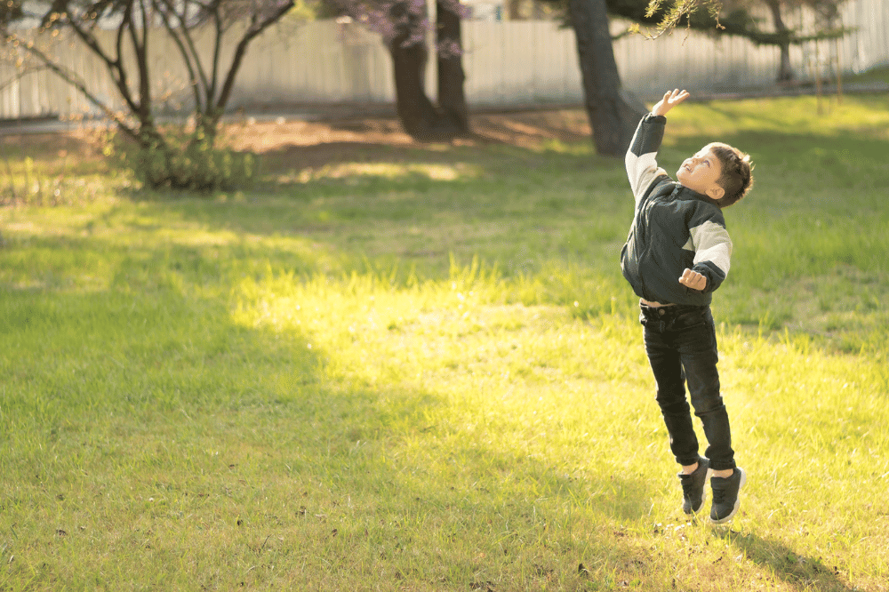 Anak laki-laki sedang bermain lompat tinggi di luar rumah