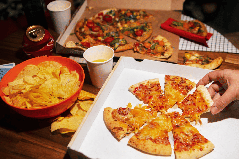 Makanan pizza, keripik kentang, dan minuman soda