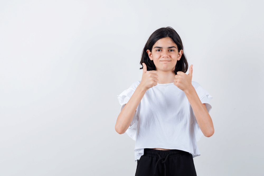 Anak perempuan mengacungkan dua jempol berarti tanda setuju