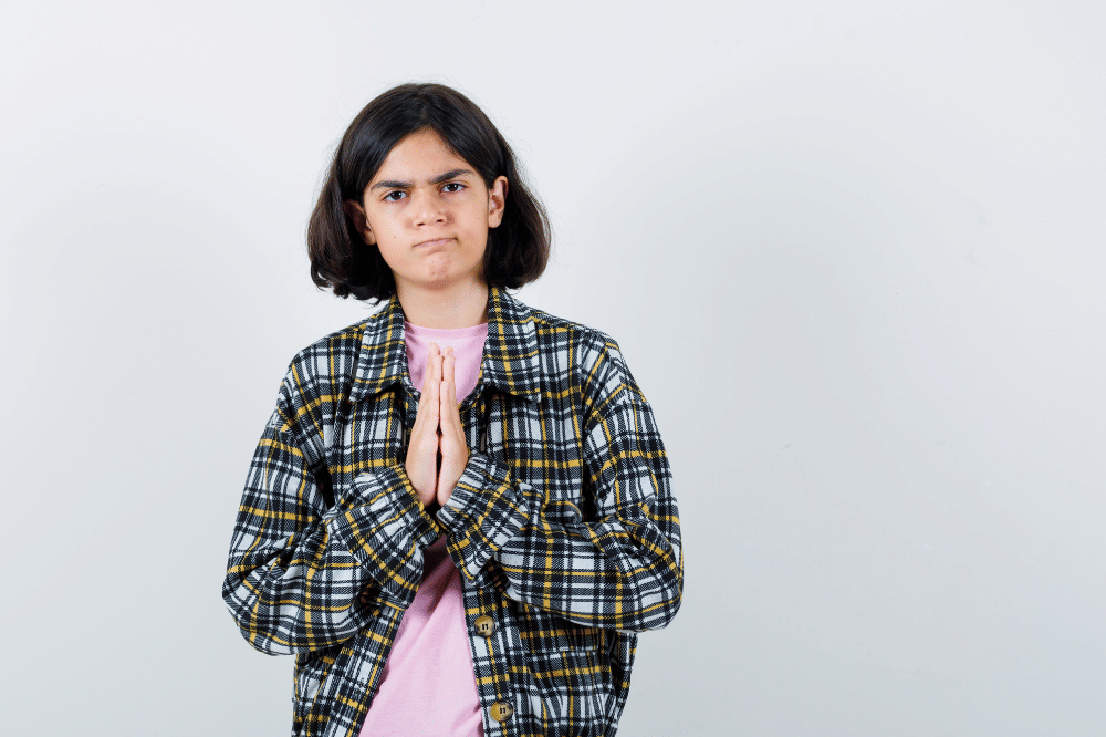 Anak perempuan sedang menangkupkan tangan seperti memohon