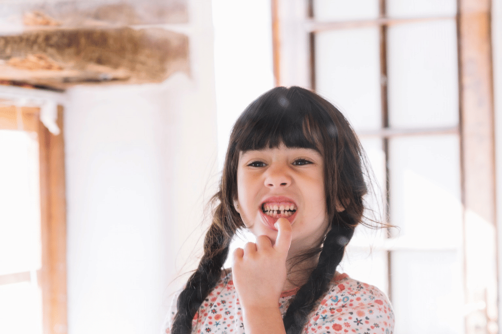 Anak perempuan sedang tersenyum sambil menunjukkan giginya