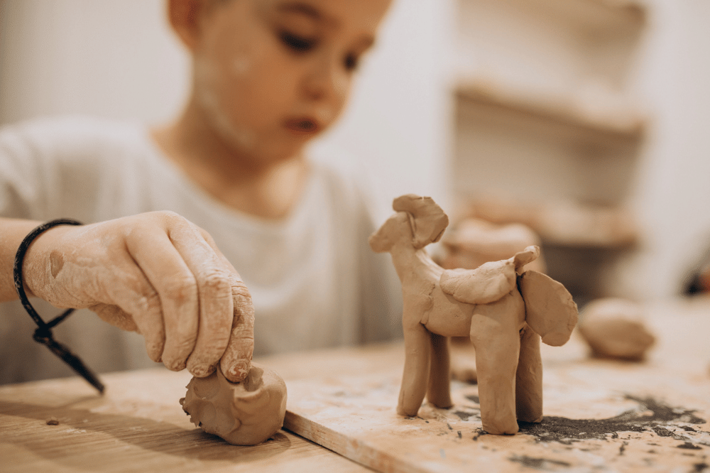 anak membentuk patung dari tanah liat