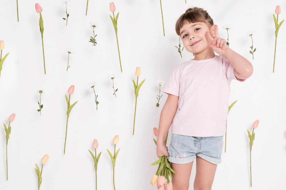 Anak perempuan berpose dengan cantik sambil memegang bunga dan background bunga