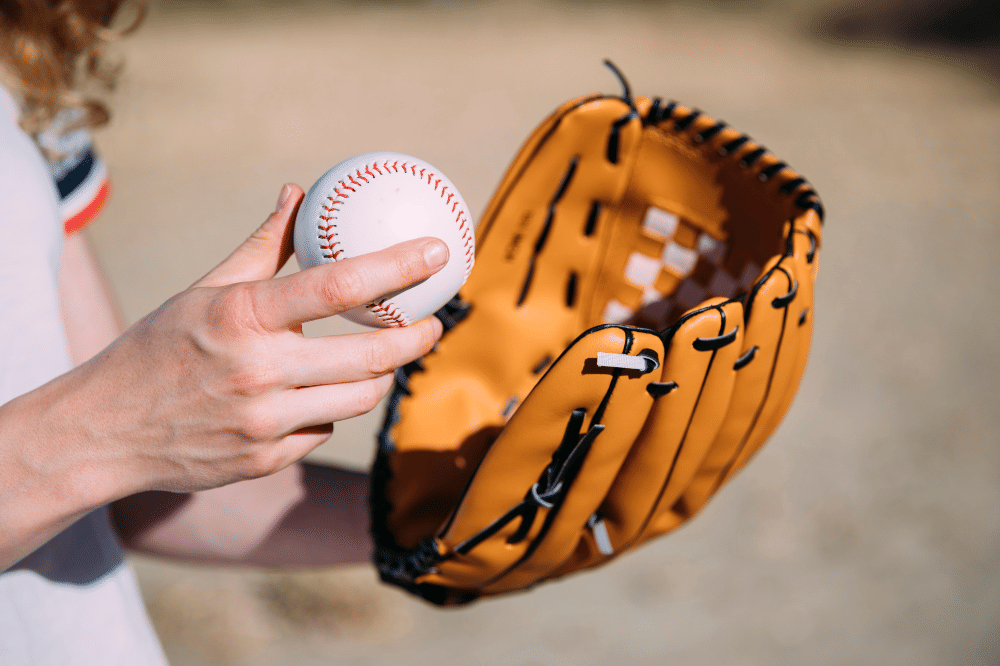 Seorang anak terlihat memakai sarung tangan dan memegang bola kasti