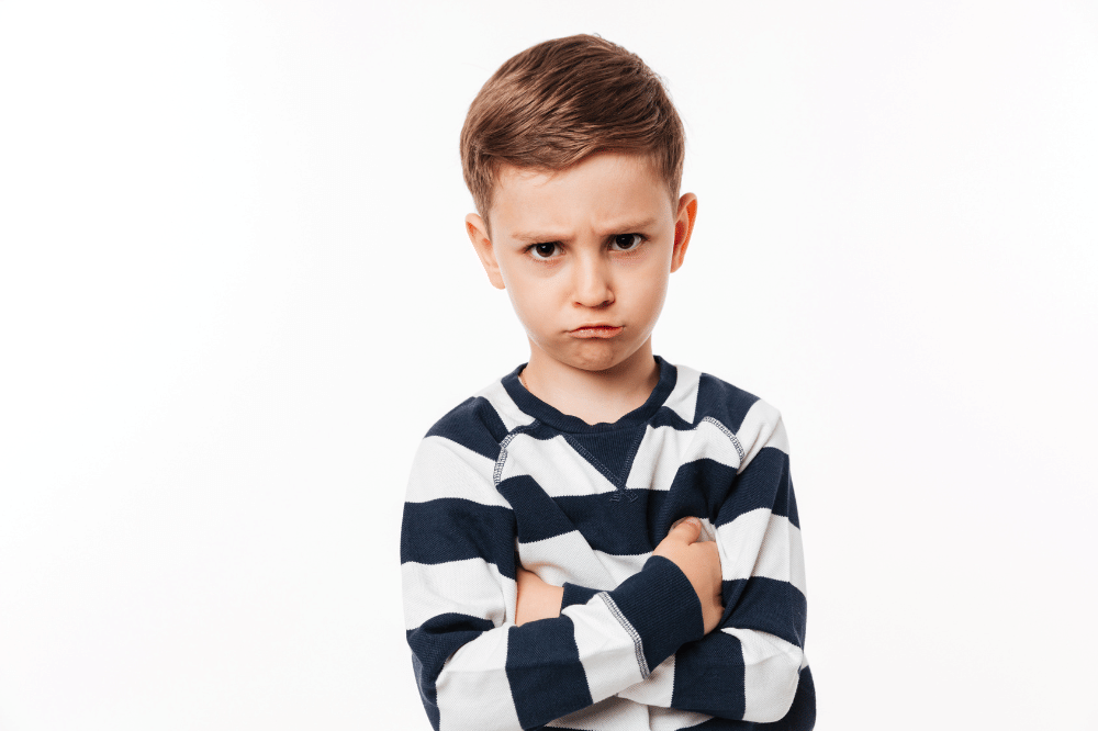 Anak laki-laki menyilangkan tangannya dengan ekspresi marah