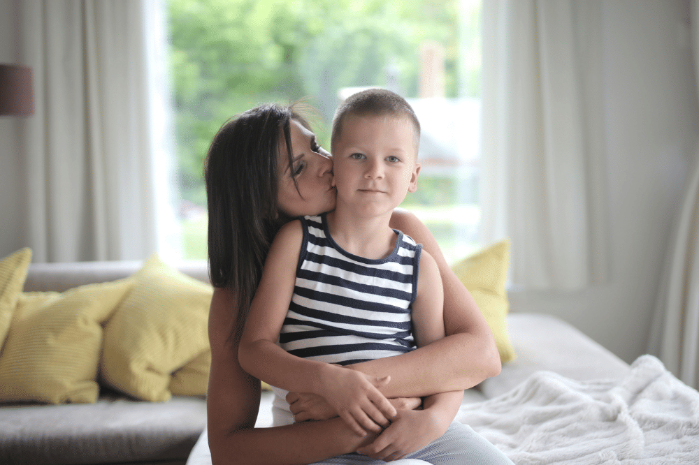 Mama sedang memangku anak laki-laki dan menicumnya