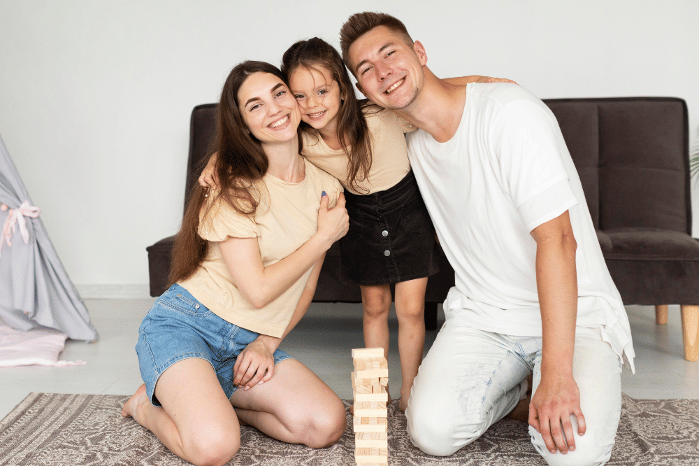 Anak perempuan memeluk Papa dan Mama sambil tersenyum