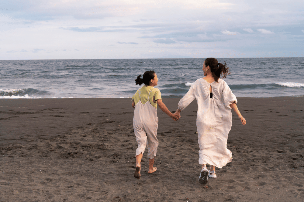 Mama dan anak perempuan menghabiskan waktu bersama sambil berlari di pantai