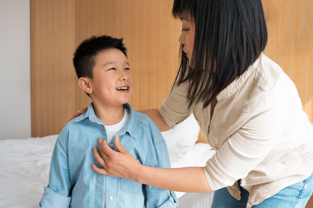 Mama dan anak laki-laki mengobrol saat Mama membantu merapikan baju anaknya