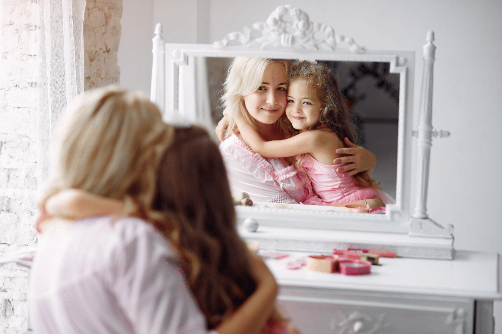 Mama dan anak perempuan sedang becermin sambil berpelukan