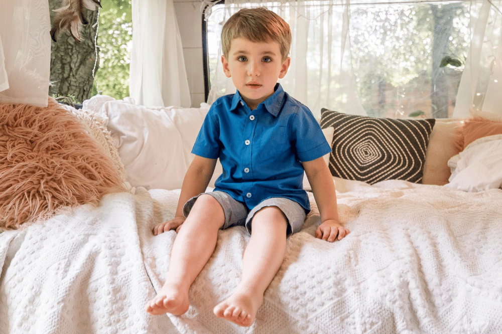 Anak laki-laki duduk di sofa karavan menghadap kamera