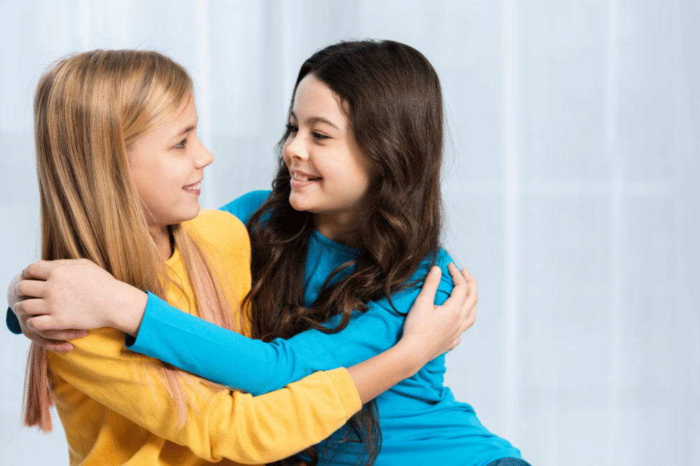 kedua anak perempuan tersebut saling berpelukan dan tersenyum