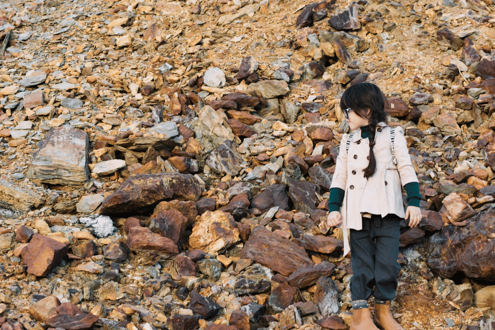 Anak perempuan sedang berdiri di bukit bebatuan