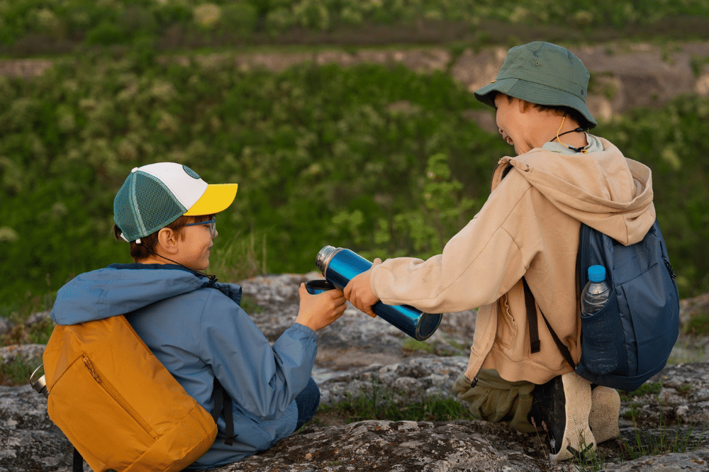 Kedua anak laki-laki sedang duduk beristirahat dan berbagi minuman