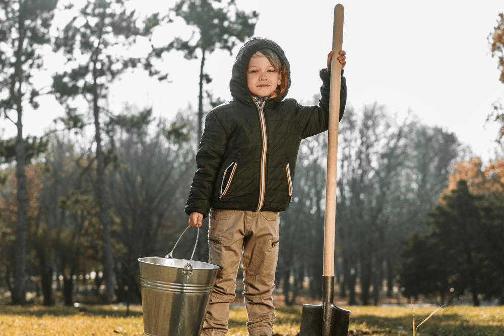 Anak laki-laki sedang memegang ember dan sekop