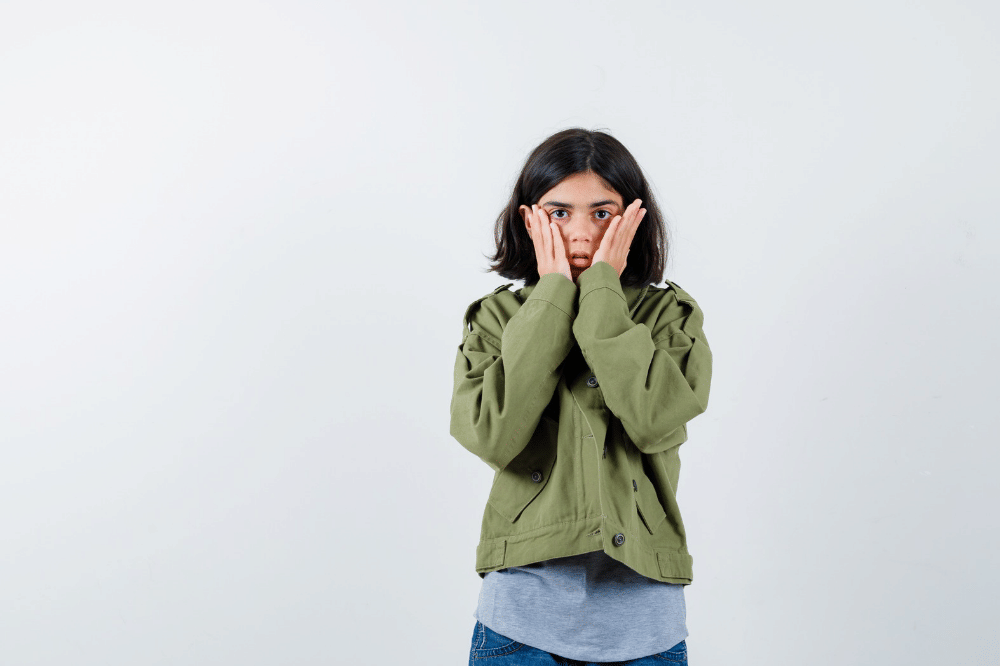 Anak perempuan menutup setengah mukanya dengan tangan karena takut