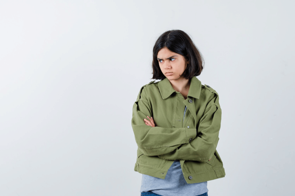 Anak perempuan tersebut menyilangkan tangan dengan ekspresi marah