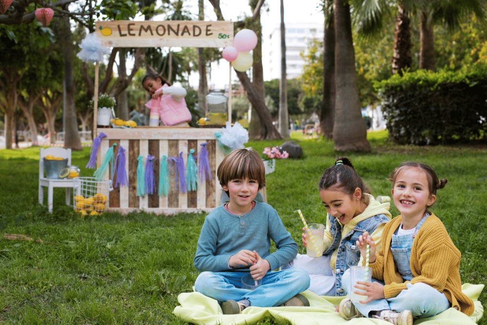 Anak-anak sedang berpiknik di taman sambil memegang lemonade