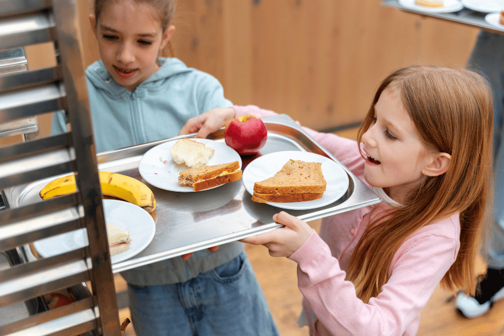 Anak-anak perempuan sedang menaruh kembali tempat bekas makannya