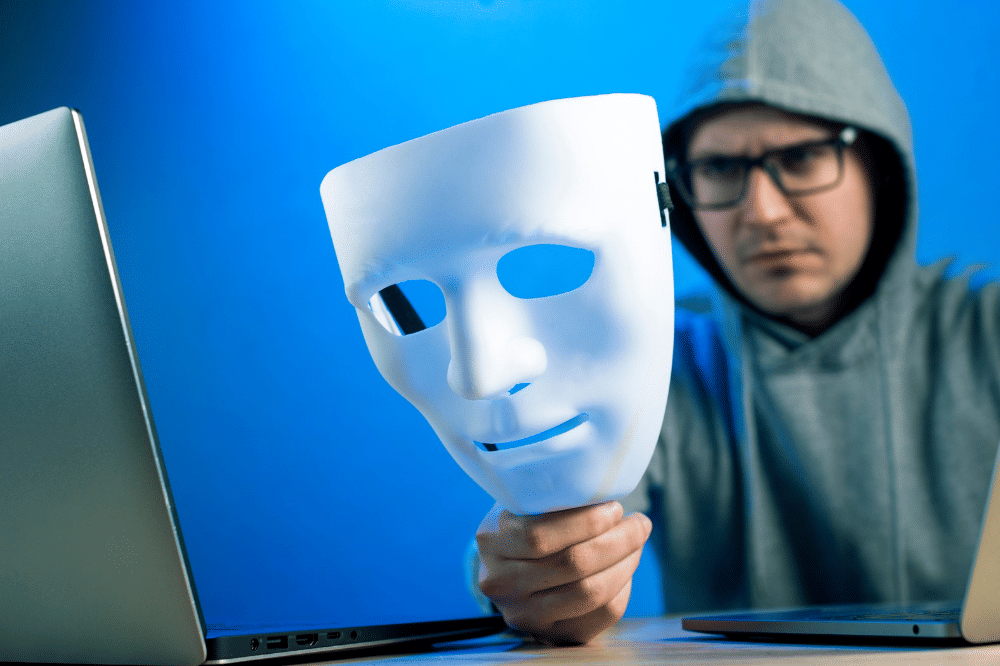 Seorang laki-laki sedang duduk di depan laptop dan memalsukan identitasnya