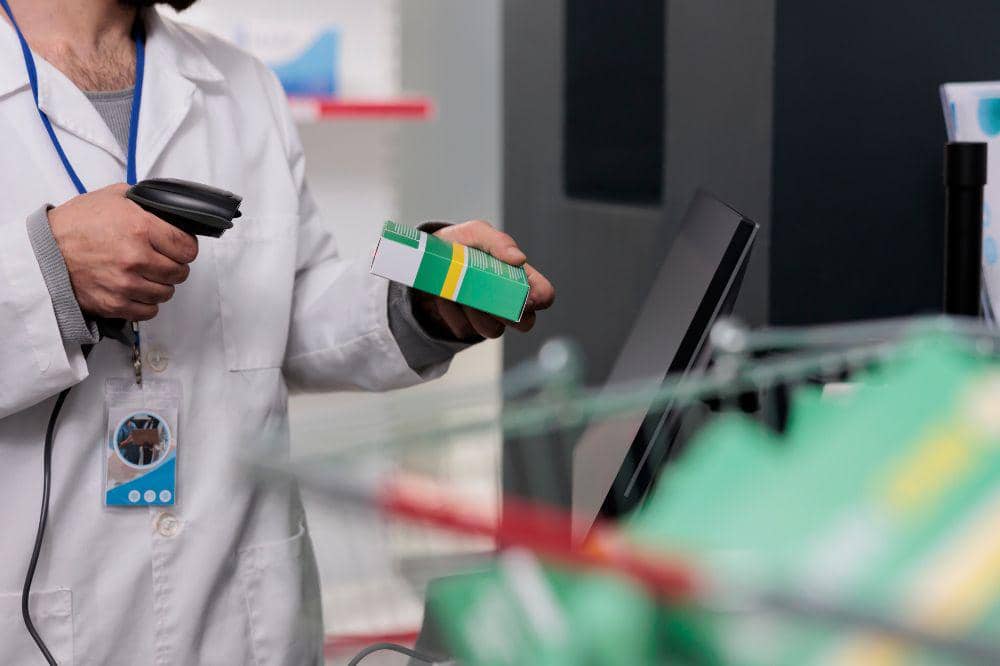 Man pharmacist holding store scanner that reads the barcodes on all the drugs and packages to ensure accuracy in dispensing medication. Pharmacy employee working in drugstore, checking supplements.jpg