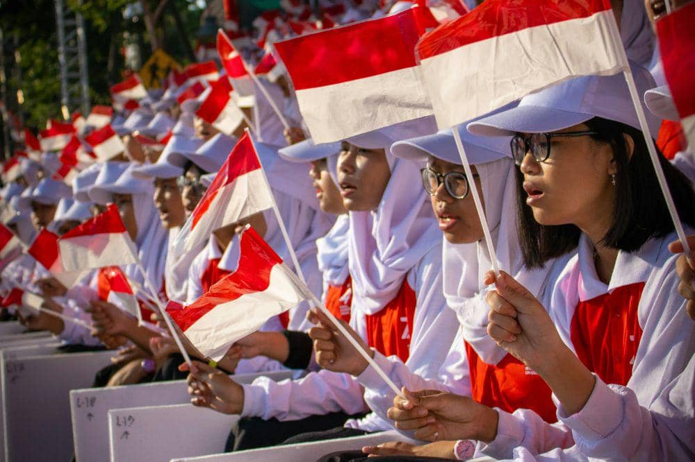 Anak mengibarkan bendera negara Indonesia