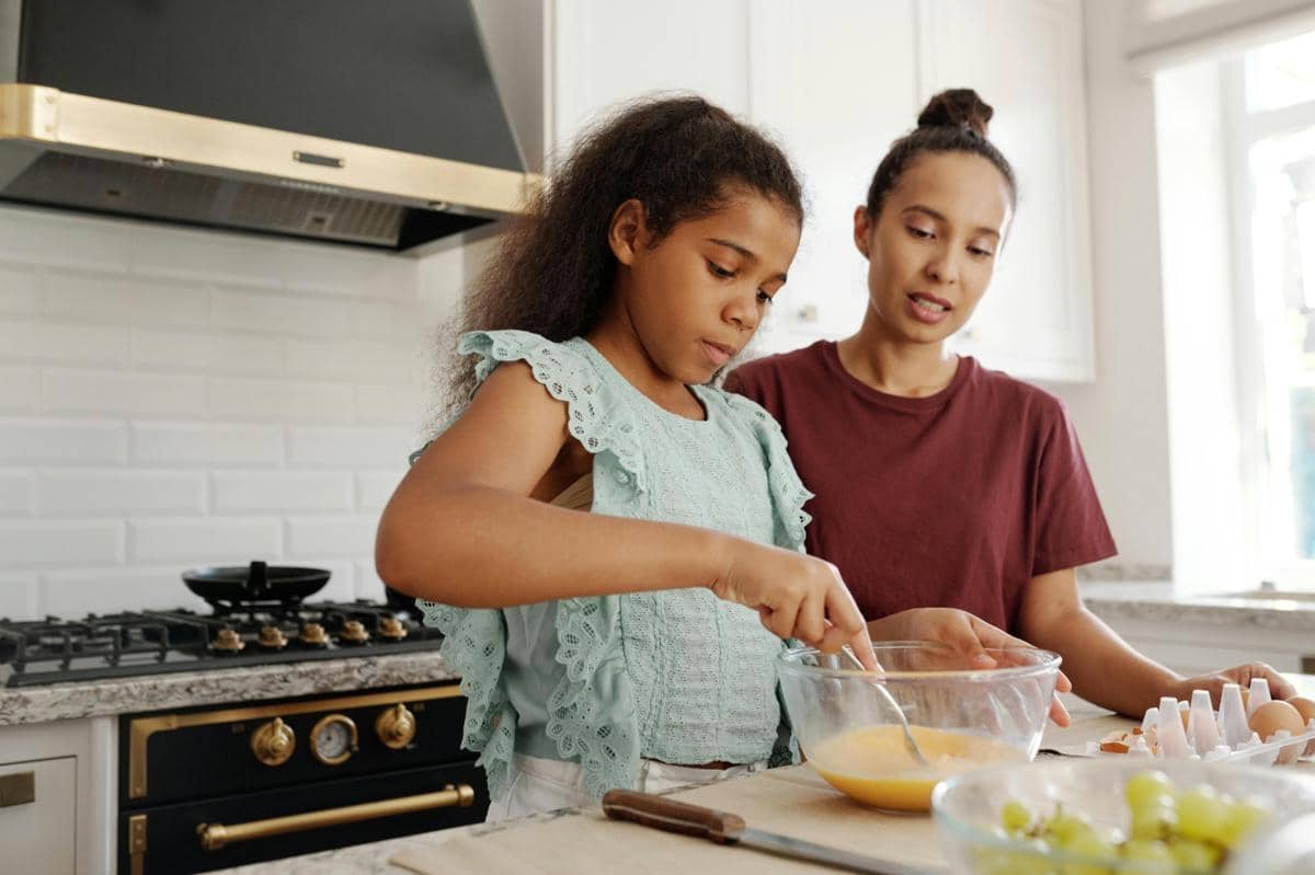 kid cooking egg with mom