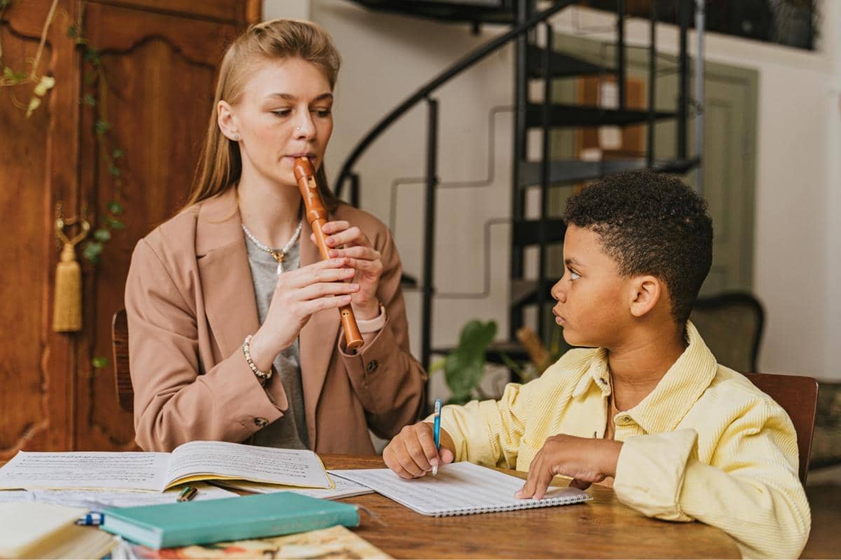 woman teaching a boy how to play the flute