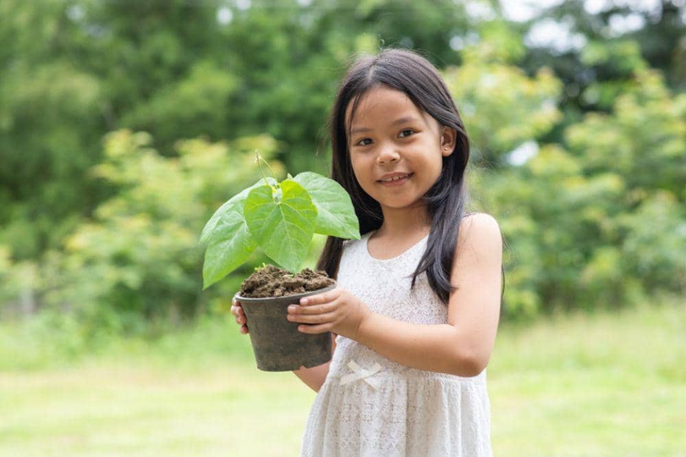 Anak memegang pot bunga