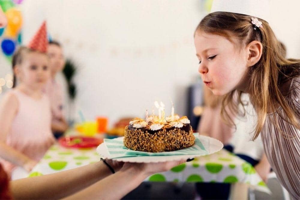 Anak meniup lilin kue ulang tahun