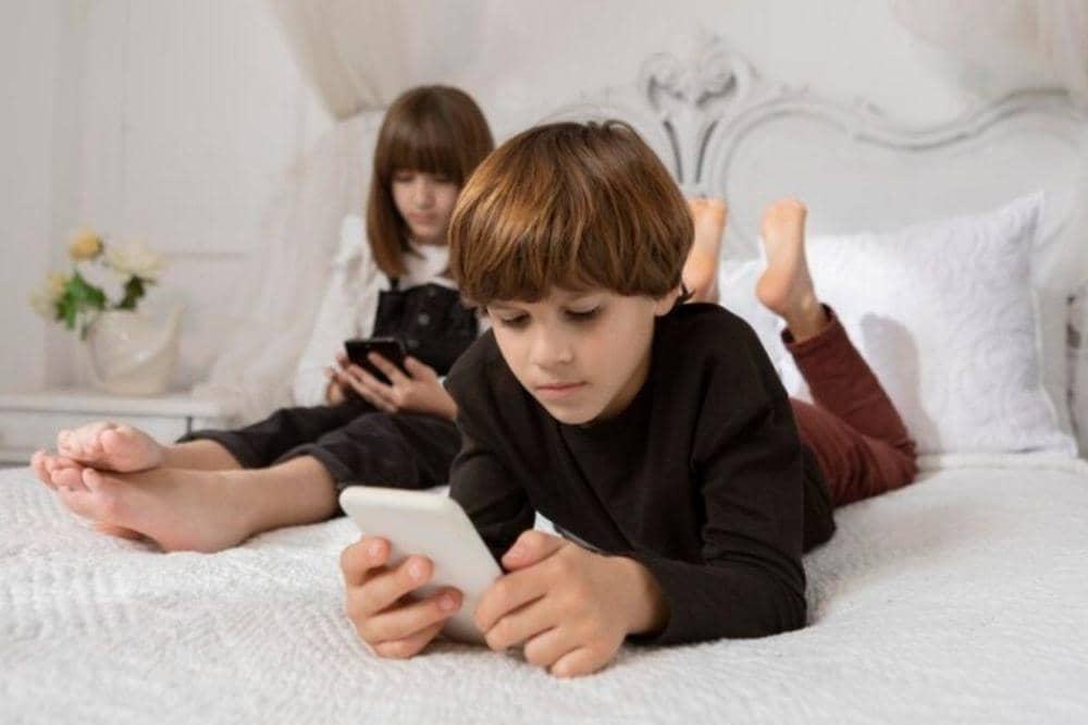 Kakak beradik sedang bermain ponsel