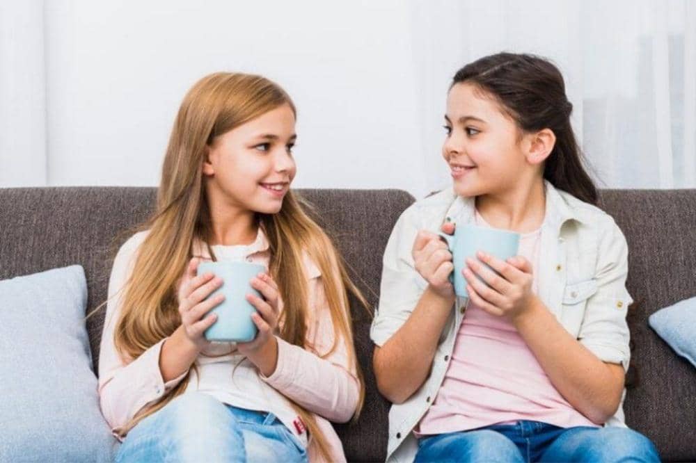 2 anak sedang duduk dan minum teh