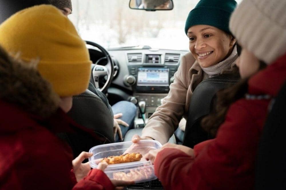 Mama dan anak makan di mobil saat mudik