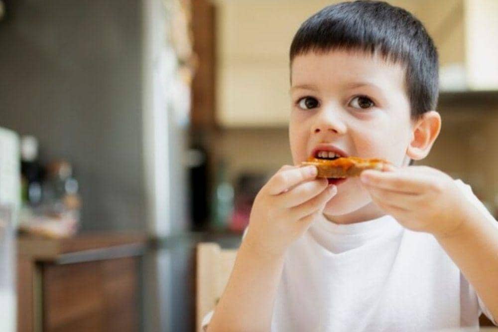 Anak laki-laki makan roti